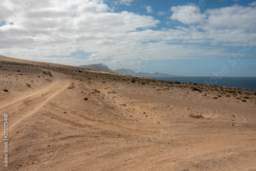 Desert road at Barlovento, Fuerteventura, Canary Islands, Spain. Ocean and high volcanic mountains in the background. 