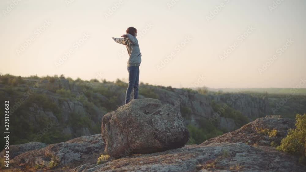A young woman traveler walks in the mountains at canyon. Sunset or sunrise slow motion shot A young woman traveler walks in the mountains at canyon. Sunset or sunrise slow motion shot