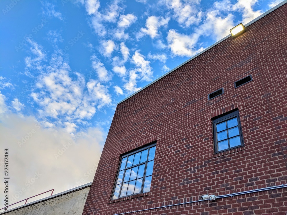 Red brick building corner against blue cloudy sky