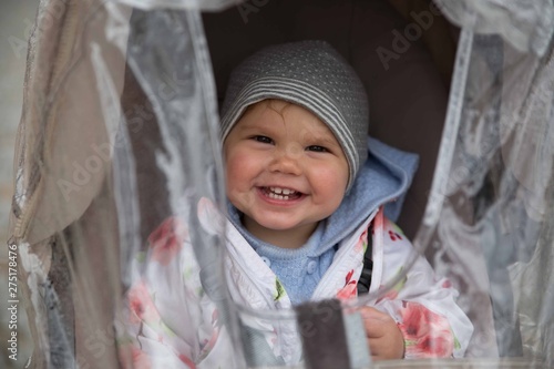 Baby girl in stroller with rain coat
