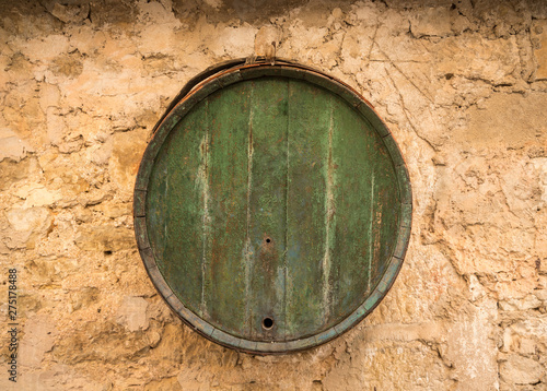 Old wooden barrel on stone farmhouse wall