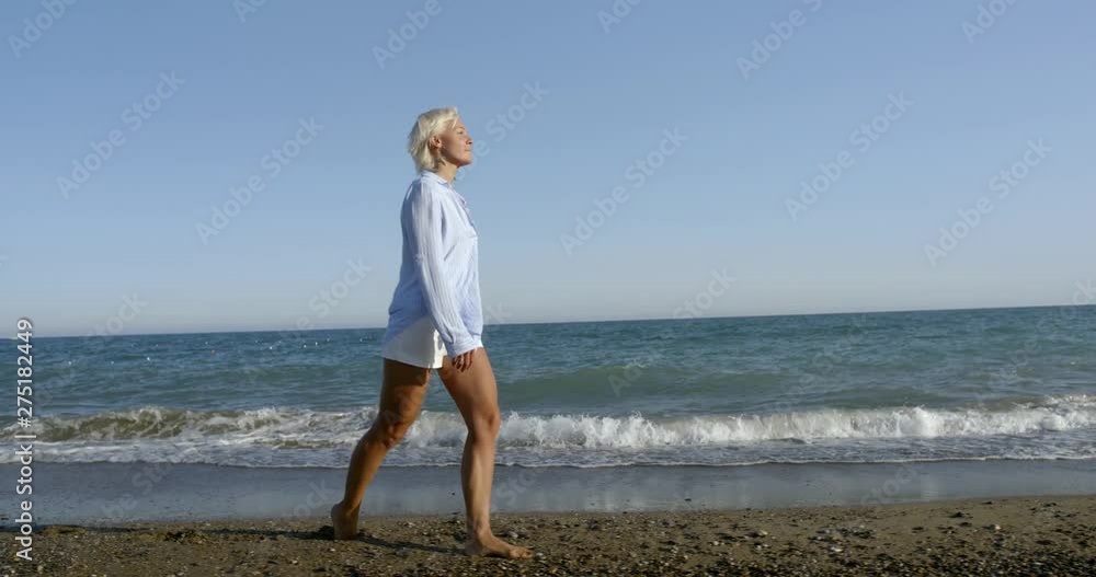 blond lady in white summer dressing walks along sandy beach blond lady in white summer dressing walks along sandy beach