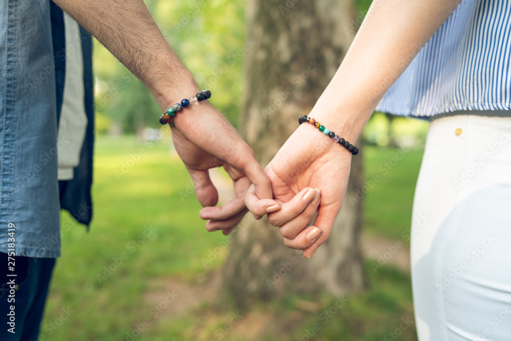 Young couple in love relationship holding hands in park midsection close up Young couple in love relationship holding hands in park midsection close up