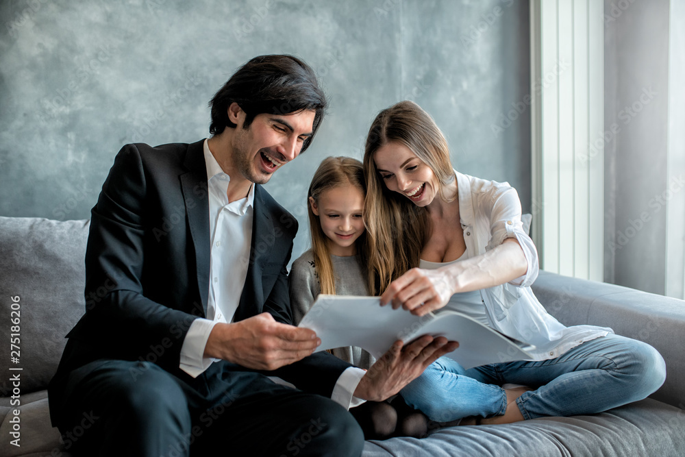 Happy little girl reads a book with her parents Happy little girl reads a book with her parents
