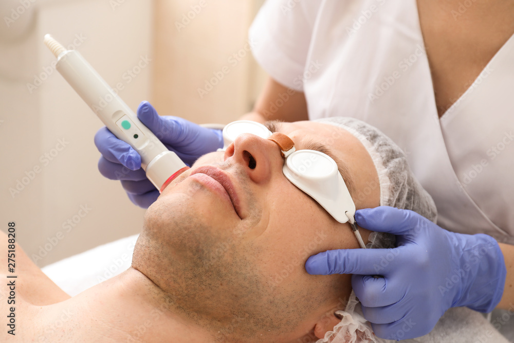 Handsome man undergoing procedure of laser biorevitalization in beauty salon Handsome man undergoing procedure of laser biorevitalization in beauty salon
