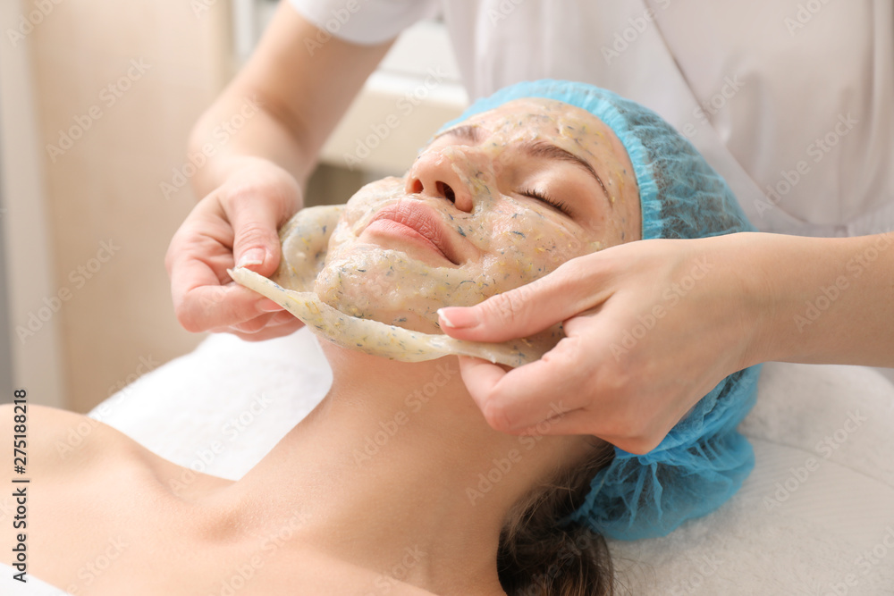 Beautiful woman undergoing treatment with facial mask in beauty salon