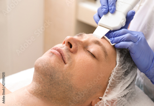 Handsome man undergoing procedure of facial peeling in beauty salon