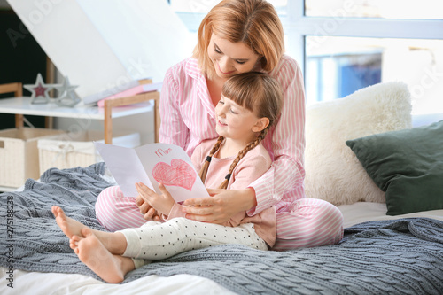 Woman with greeting card for Mother's Day received from her little daughter at home photo