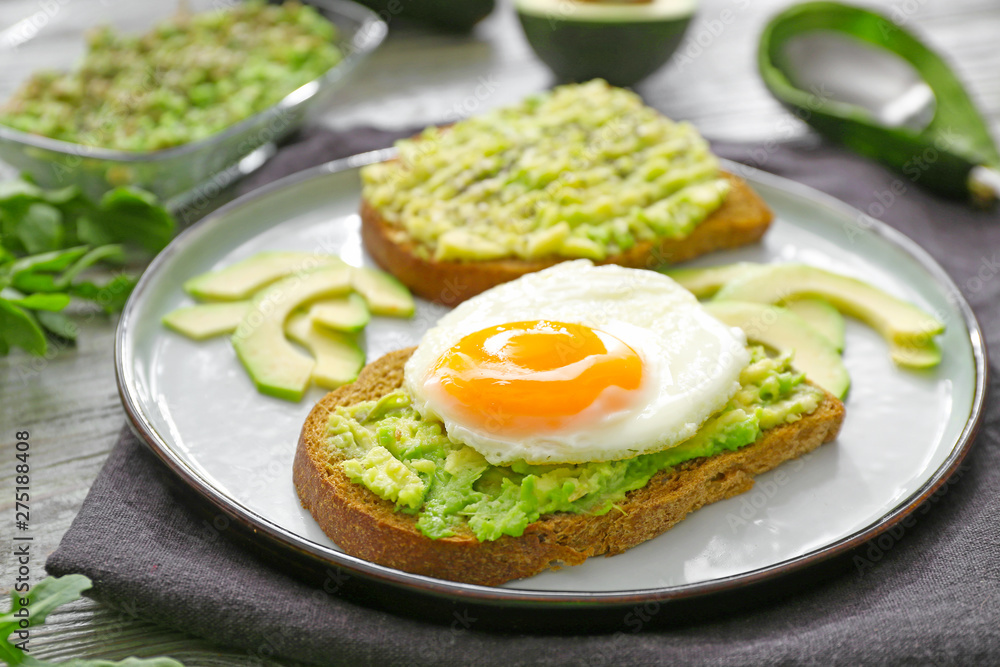 Plate with tasty avocado toasts on table