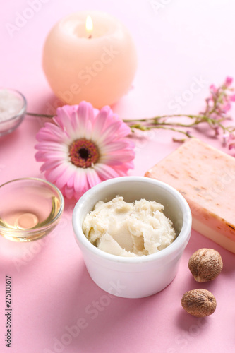 Shea butter with cosmetic products and candle on color background