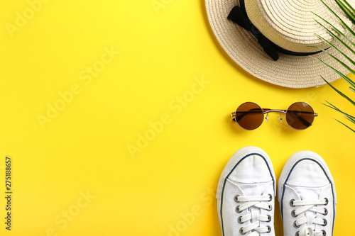 Stylish sunglasses with gumshoes and hat on color background photo