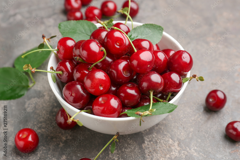 Bowl with ripe cherry on grey background Bowl with ripe cherry on grey background