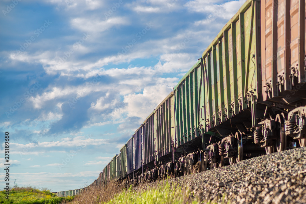 Rural summer landscape with freight train passing field at sunny day Rural summer landscape with freight train passing field at sunny day