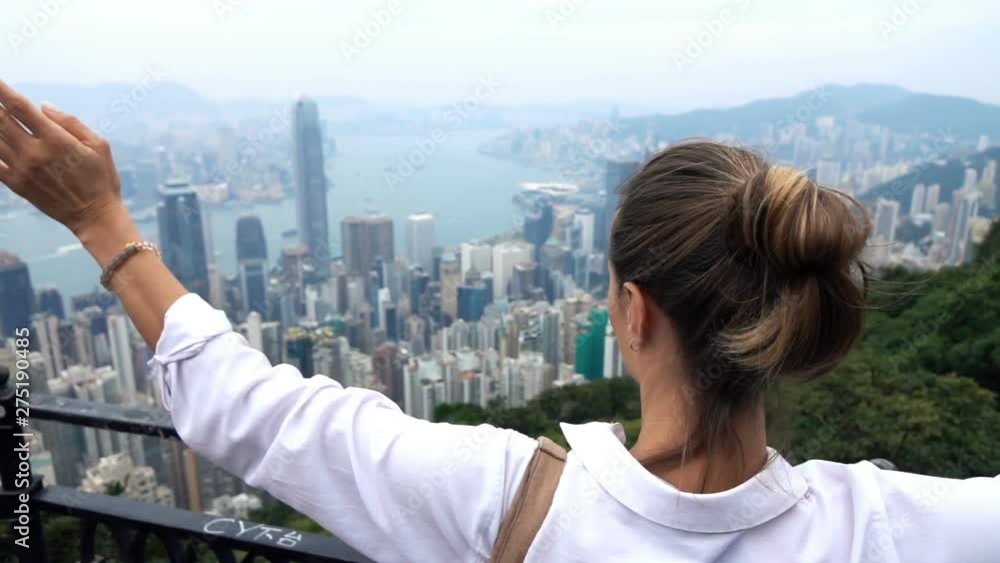 Happy woman raising arms in triumph at Hong Kong viewpoint, slow motion Happy woman raising arms in triumph at Hong Kong viewpoint, slow motion
