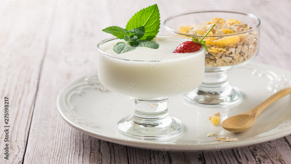 Bowl of yogurt and strawberries with mint and bowl of oatmeal on a wooden table. Bowl of yogurt and strawberries with mint and bowl of oatmeal on a wooden table.