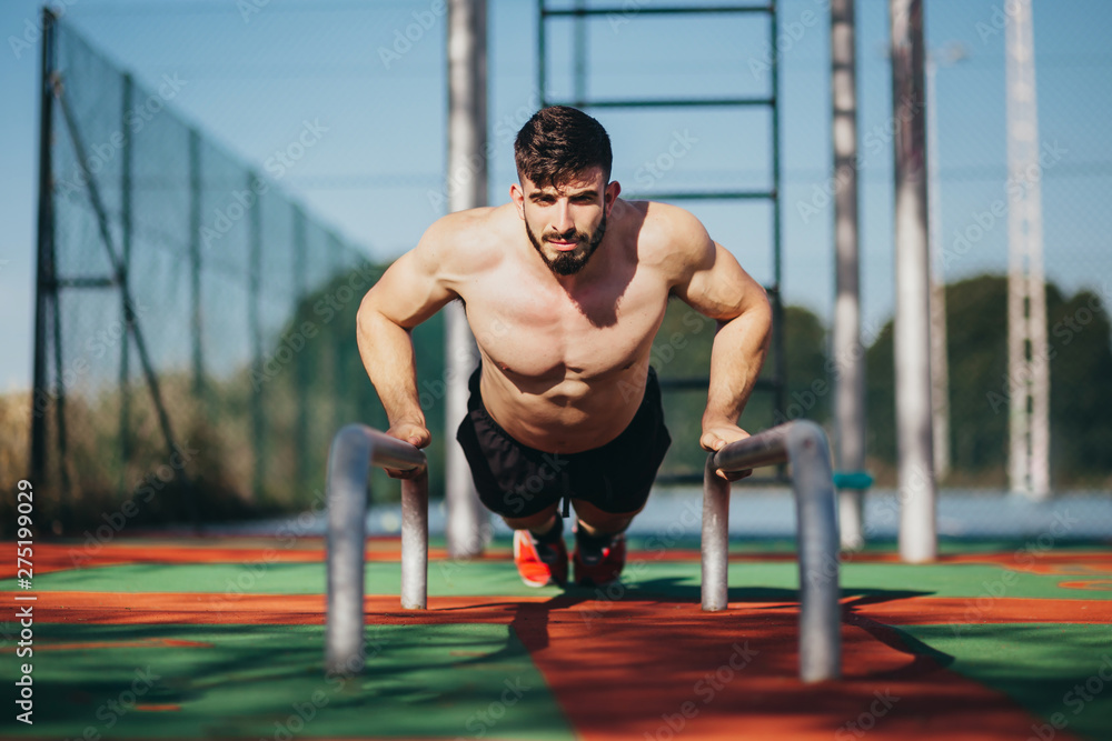 Fototapeta premium man performing push-ups on some calisthenics bars