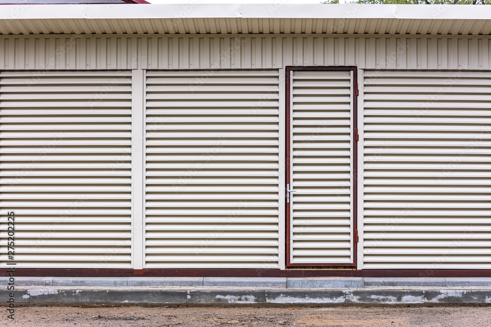 exterior view of warehouse with locked door. metal sheet louvers on wall for ventilation