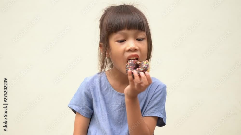 5 years old Asian girl eating donuts deliciously 5 years old Asian girl eating donuts deliciously