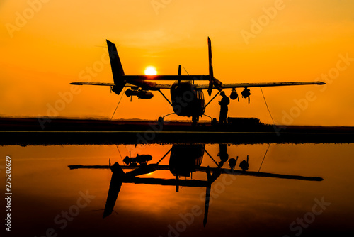 The silhouette helicopter parking landing on offshore platform and refection picture on ground floor at sun set sky background.