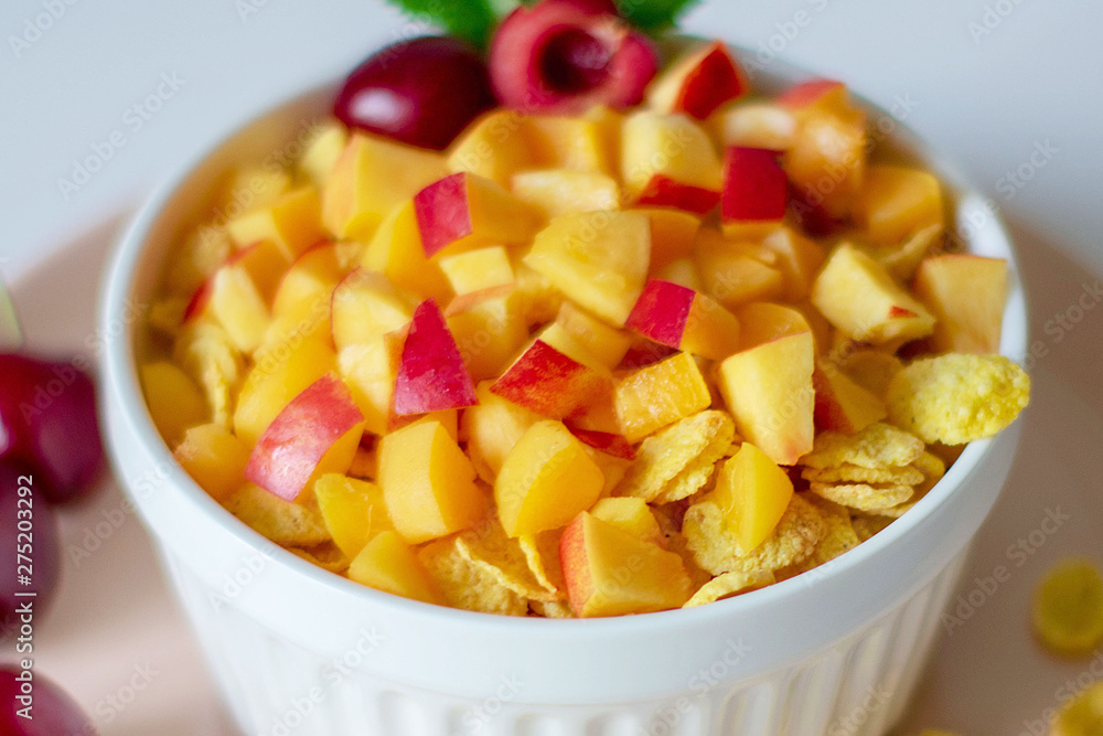 Healthy breakfast with cornflakes and pieces of fruit, cherries on a white background Healthy breakfast with cornflakes and pieces of fruit, cherries on a white background