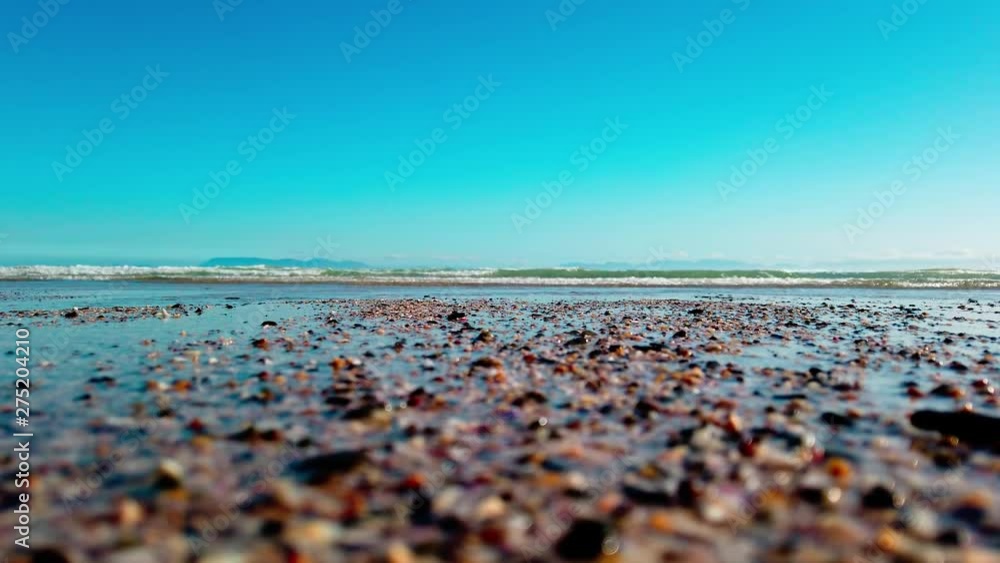 Close Up: Turquoise ocean waves roll in on the peaceful shore with sea birds in the background. View of swell reaching sandy beach. Close Up: Turquoise ocean waves roll in on the peaceful shore with sea birds in the background. View of swell reaching sandy beach.