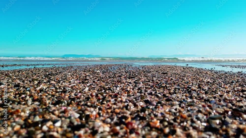 Close Up: Turquoise ocean waves roll in on the peaceful shore with sea birds in the background. View of swell reaching sandy beach. Close Up: Turquoise ocean waves roll in on the peaceful shore with sea birds in the background. View of swell reaching sandy beach.
