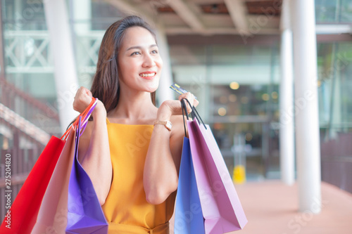 Beautiful women with shopping bags and credit card enjoying in shopping standing outdoors of shopping mall, shopping concept