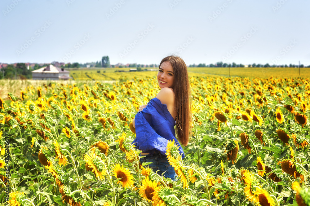 Young happy girl on a walk in a field with sunflowers Young happy girl on a walk in a field with sunflowers