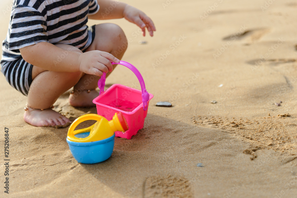 boy playing with beach toys on the beach in summertime - childhood and summer concept boy playing with beach toys on the beach in summertime - childhood and summer concept