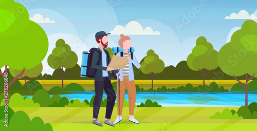 couple hikers with backpacks holding travel map man woman planning the route hiking concept travelers on hike river landscape background full length horizontal flat