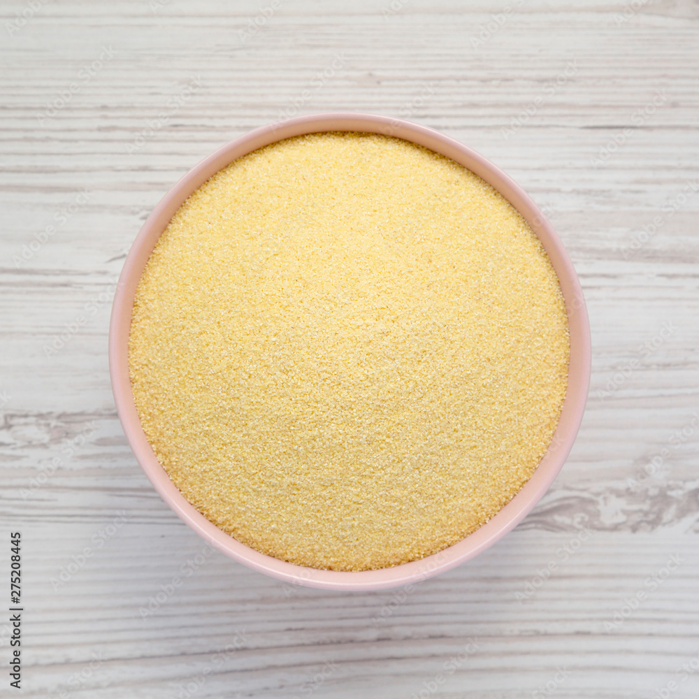 Top view, dry semolina durum flour in a pink bowl over white wooden surface. Overhead, from above, flat lay. Top view, dry semolina durum flour in a pink bowl over white wooden surface. Overhead, from above, flat lay.