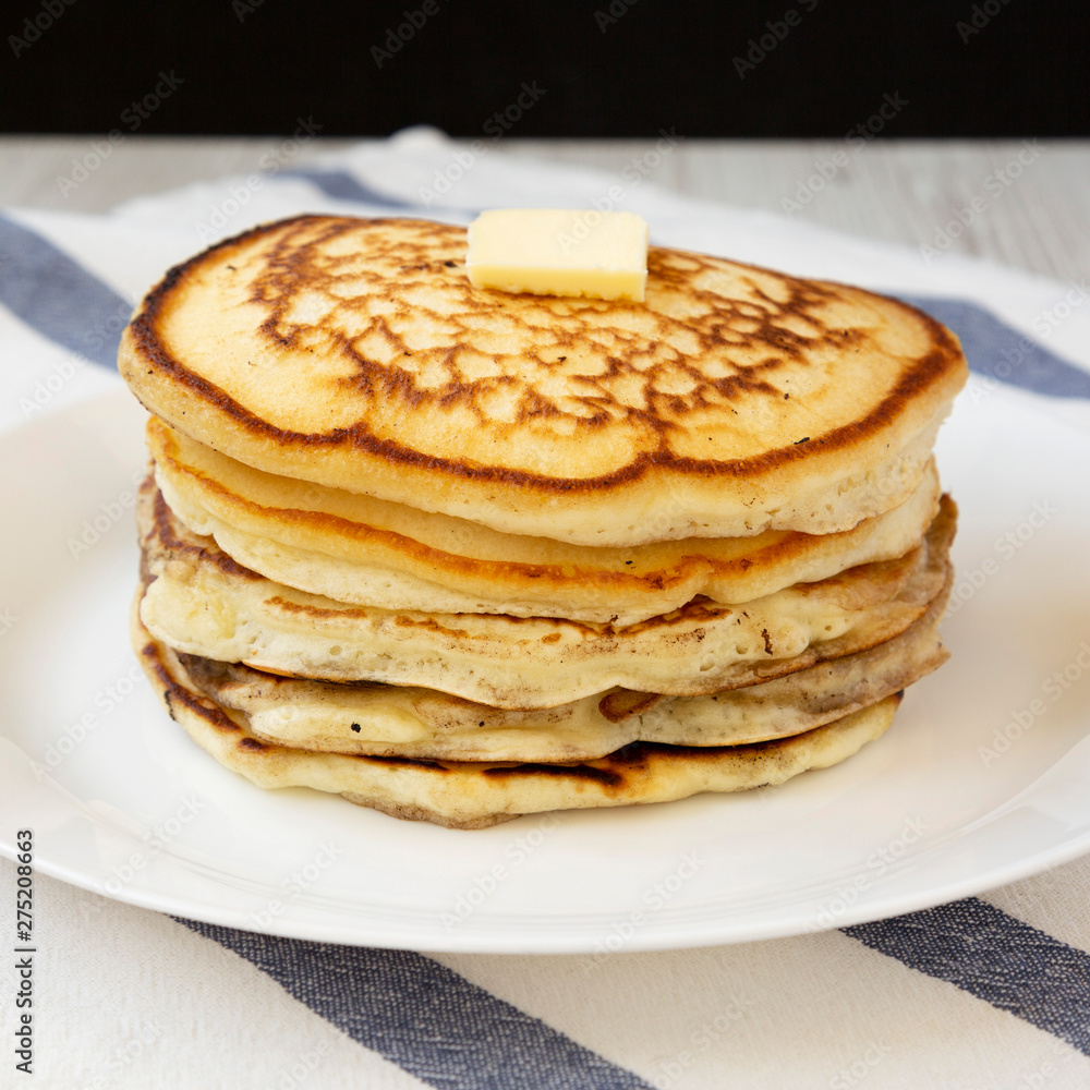 Homemade pancakes with butter on a white plate, side view. Closeup. Homemade pancakes with butter on a white plate, side view. Closeup.