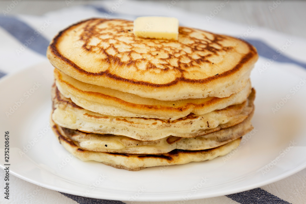 Homemade pancakes with butter on a white plate, side view. Close-up. Homemade pancakes with butter on a white plate, side view. Close-up.