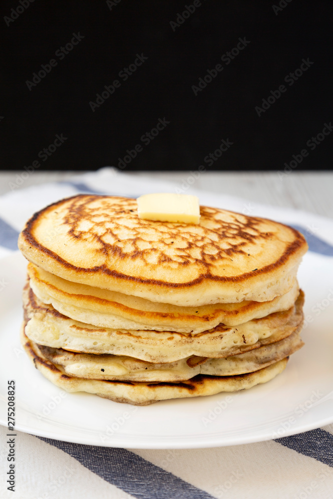 Homemade pancakes with butter on a white plate, side view. Close-up.