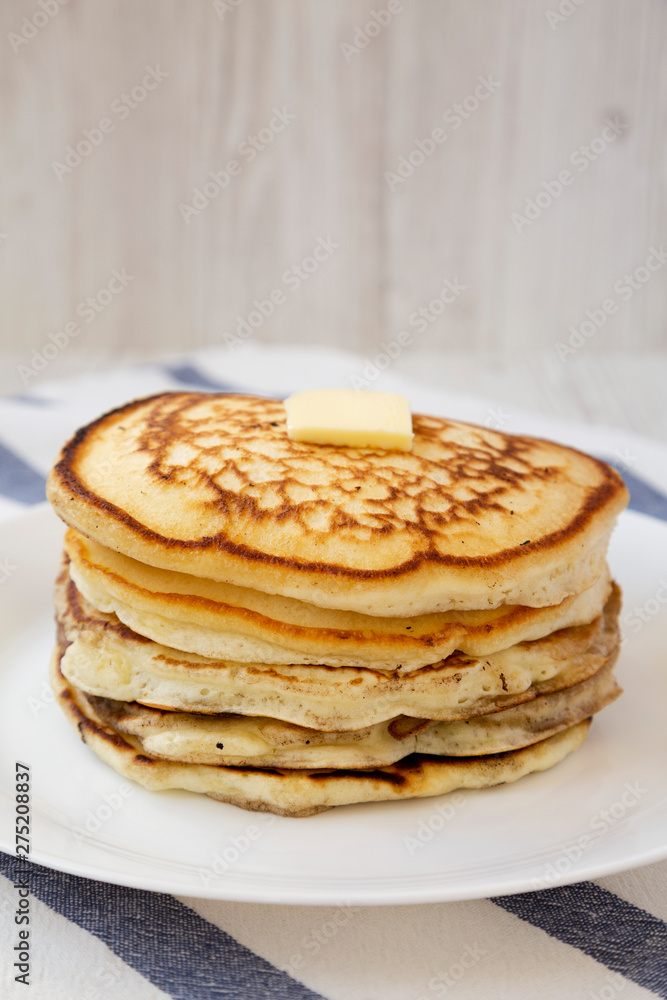 Homemade pancakes with butter on a white plate, side view. Close-up. Homemade pancakes with butter on a white plate, side view. Close-up.