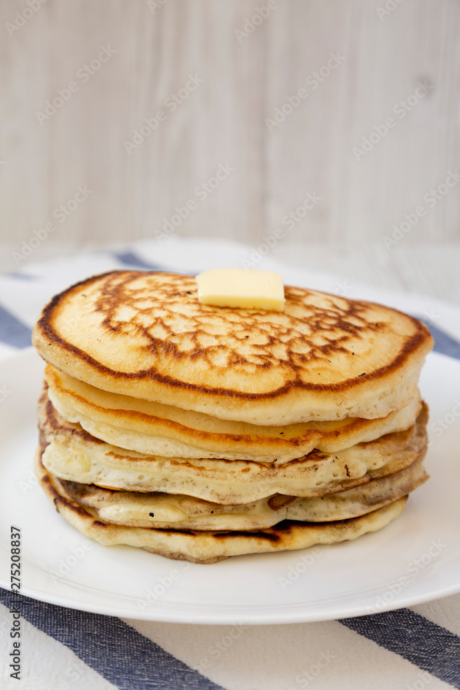 Homemade pancakes with butter on a white plate, side view. Close-up.