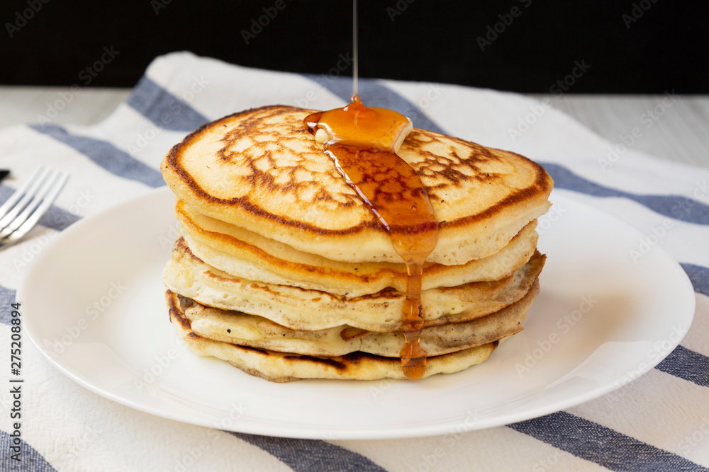 Homemade pancakes with butter and maple syrup on a white plate, side view. Closeup. Homemade pancakes with butter and maple syrup on a white plate, side view. Closeup.