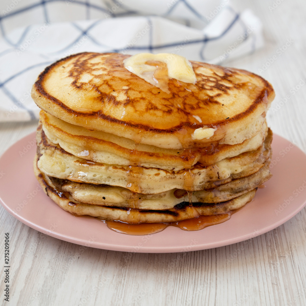 Homemade pancakes with butter and maple syrup on a pink plate, low angle view. Close-up. Homemade pancakes with butter and maple syrup on a pink plate, low angle view. Close-up.