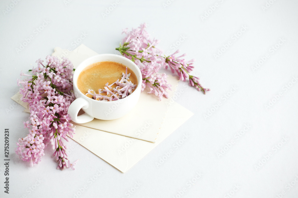 Minimal elegant composition with coffee cup and lilac branches, envelope on white background, female morning breakfast, woman mother day, saint valentine day Minimal elegant composition with coffee cup and lilac branches, envelope on white background, female morning breakfast, woman mother day, saint valentine day