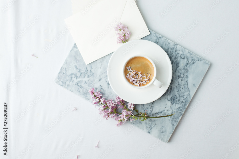 Minimalistic still life with coffee and lilac branches on marble plate and the white table, morning female concept, copy space Minimalistic still life with coffee and lilac branches on marble plate and the white table, morning female concept, copy space