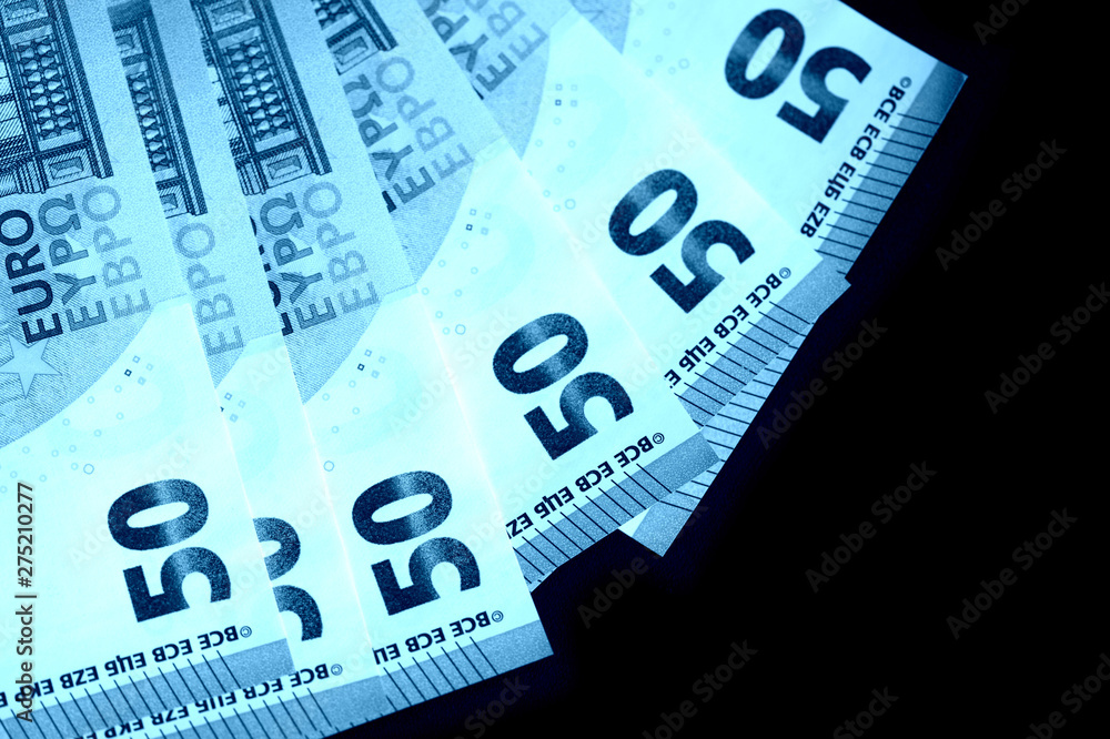 Fototapeta premium Fifty euro notes on a dark background close up. Blue color toned