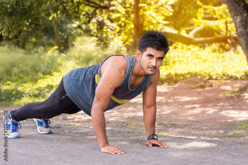 Young fit Caucasian man doing push-ups outdoors on sunny summer day. Fitness and sport lifestyle concept.