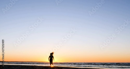 Silhouette of young woman doing exercises on the sea beach during sunset. Yoga. Fitness and a healthy lifestyle. Concept of: Running Sport Woman, Sportm  Lifestyle, Sun, Sea, Summer. photo