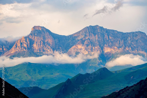 Scenic view of foggy mountains. Sunlit rocks and clouds