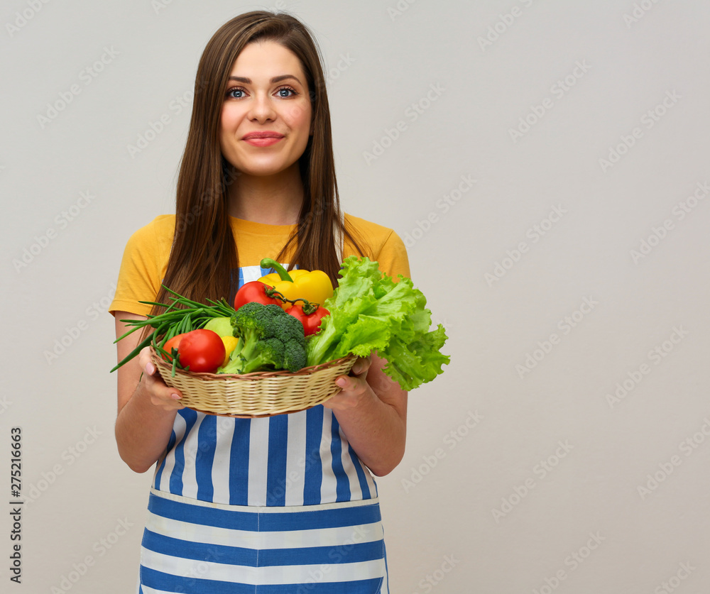 Cook woman wearing apron holding vegetables and greenery Cook woman wearing apron holding vegetables and greenery
