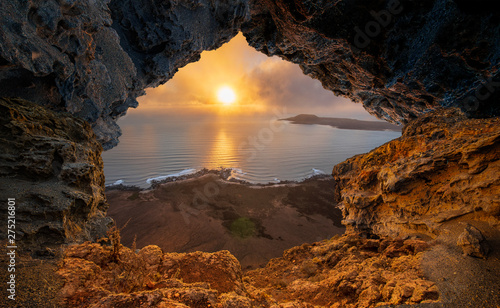 A view from a natural rock cave to the ocean during sunset