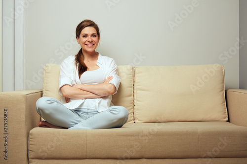 Smiling woman sitting on sofa with his legs.