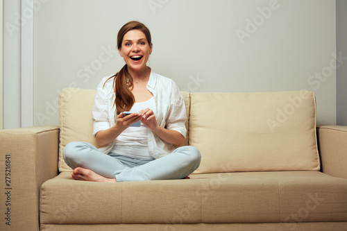 woman sitting on sofa using cell smart phone with mobile internet.