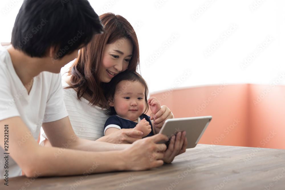 子供にタブレットを見せる両親 子供にタブレットを見せる両親