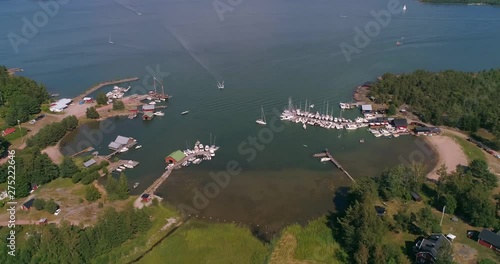 Aerial, tilt up, drone shot, away from a small harbor, full of boats, on Hogsara Island, in the finnish archipelago, on a sunny, summer day, in Varsinais-suomi, Finland photo